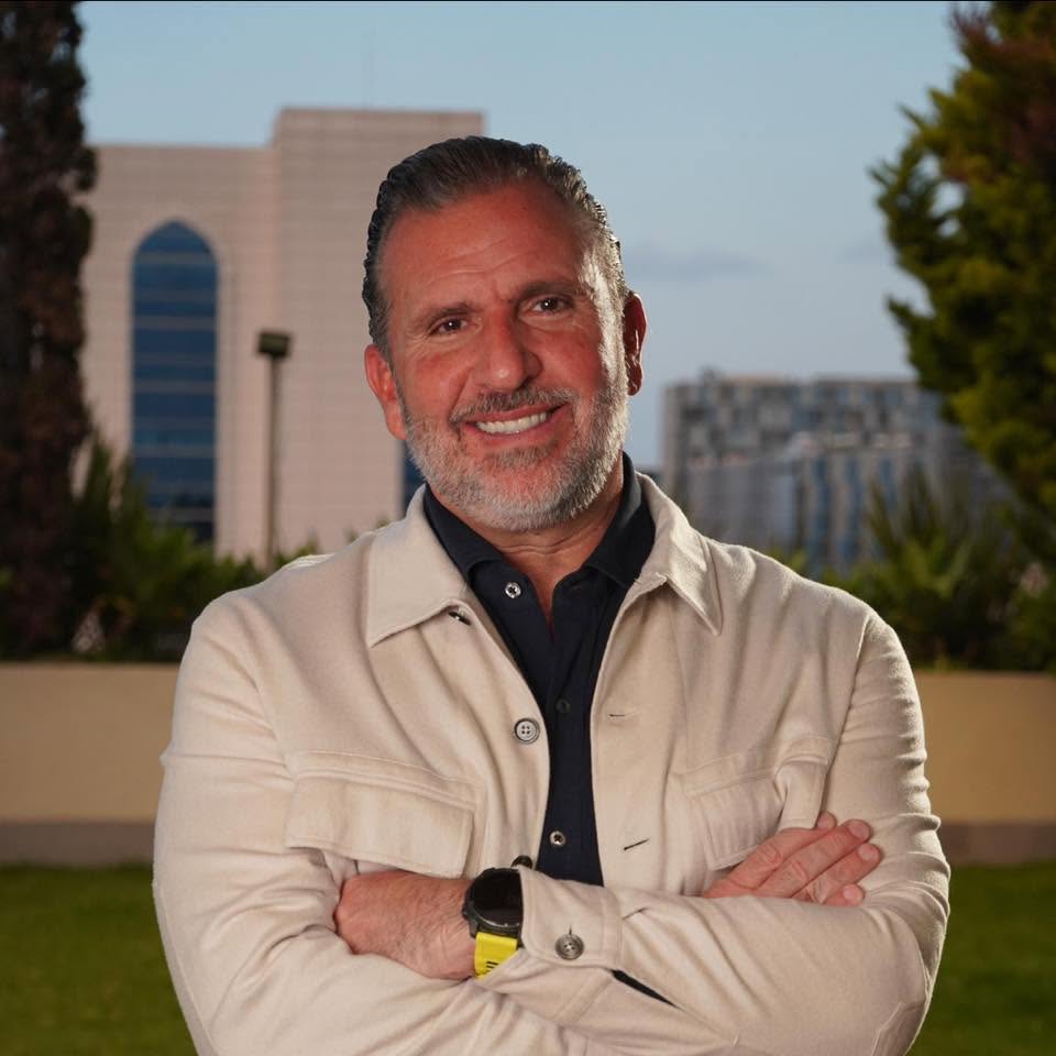 Roberto Arzú García-Granados smiling with arms crossed, wearing a light jacket outdoors